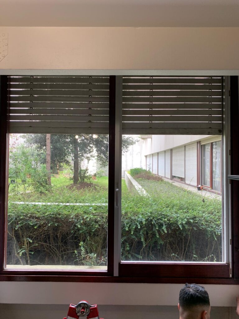 Volet roulant Velux à moitié fermé vu depuis l’intérieur avec vue sur jardin