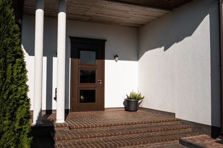 Entrée de maison rénovée avec marquise, porte d'entrée et volets assortis au style de la façade